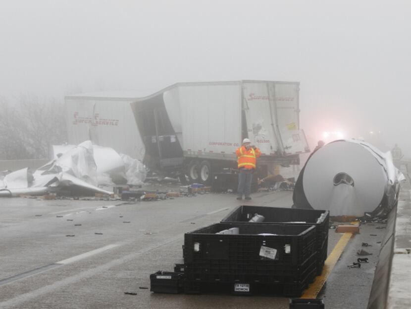 Work crews cleaned up debris in the fog on the eastbound side of I-30 after an accident...