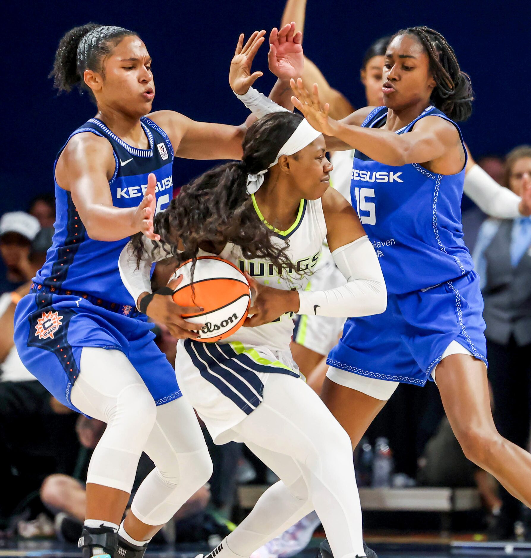 Dallas Wings guard Arike Ogunbowale (24, center) is guarded by Connecticut Sun forward...