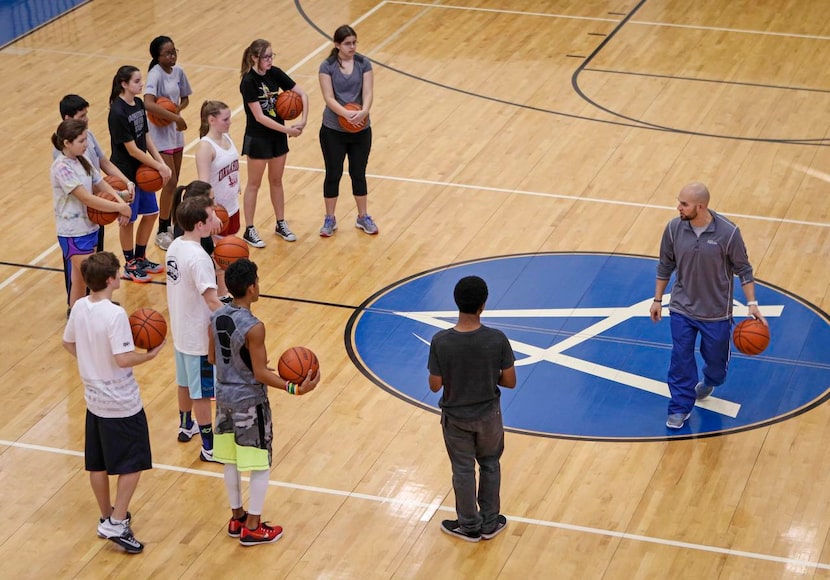 
Physical education teacher Andy Silverman works on basketball skills with a class of...