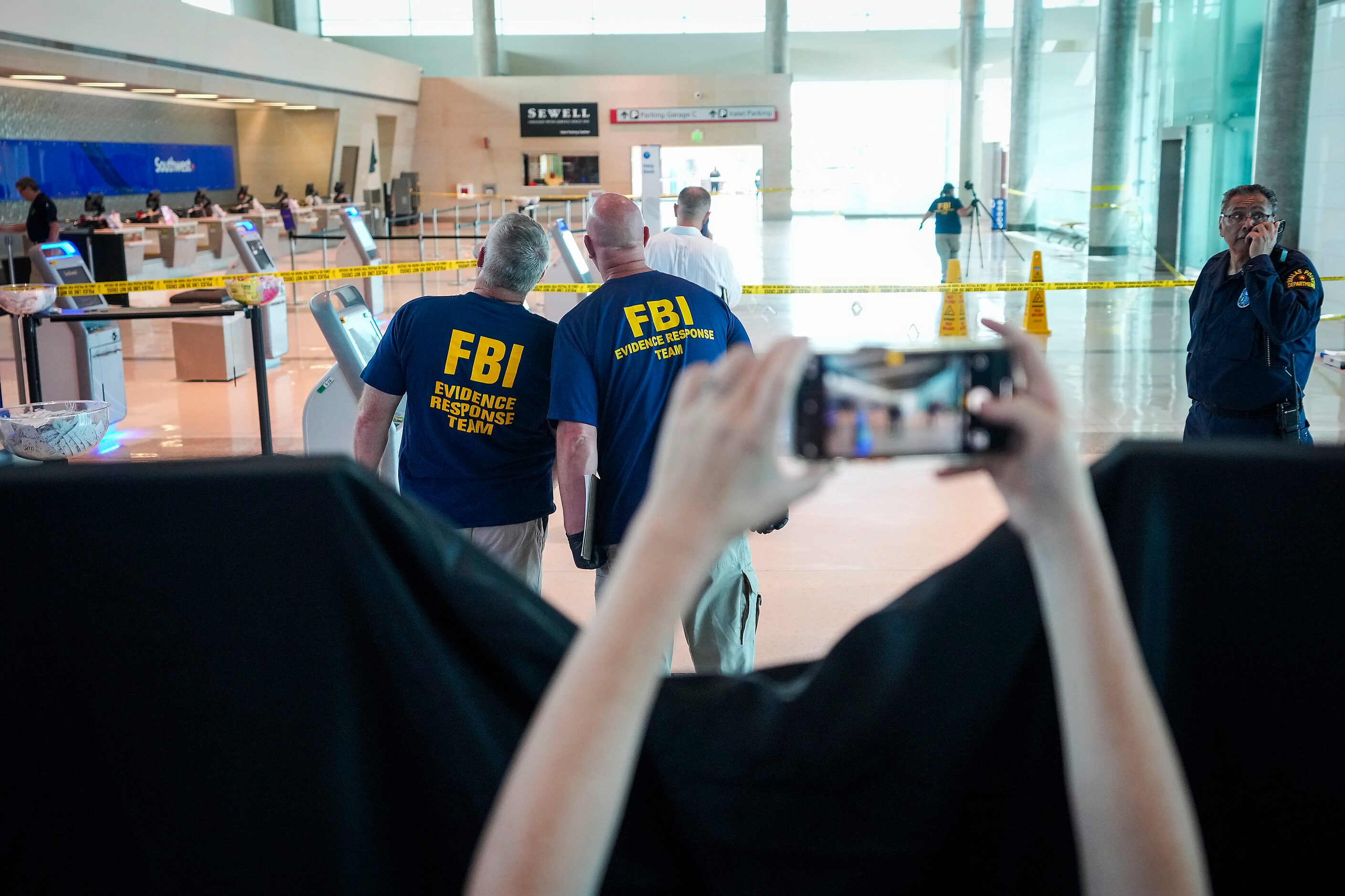 A passenger raises their phone over a curtain separating the Southwest ticket counters from...