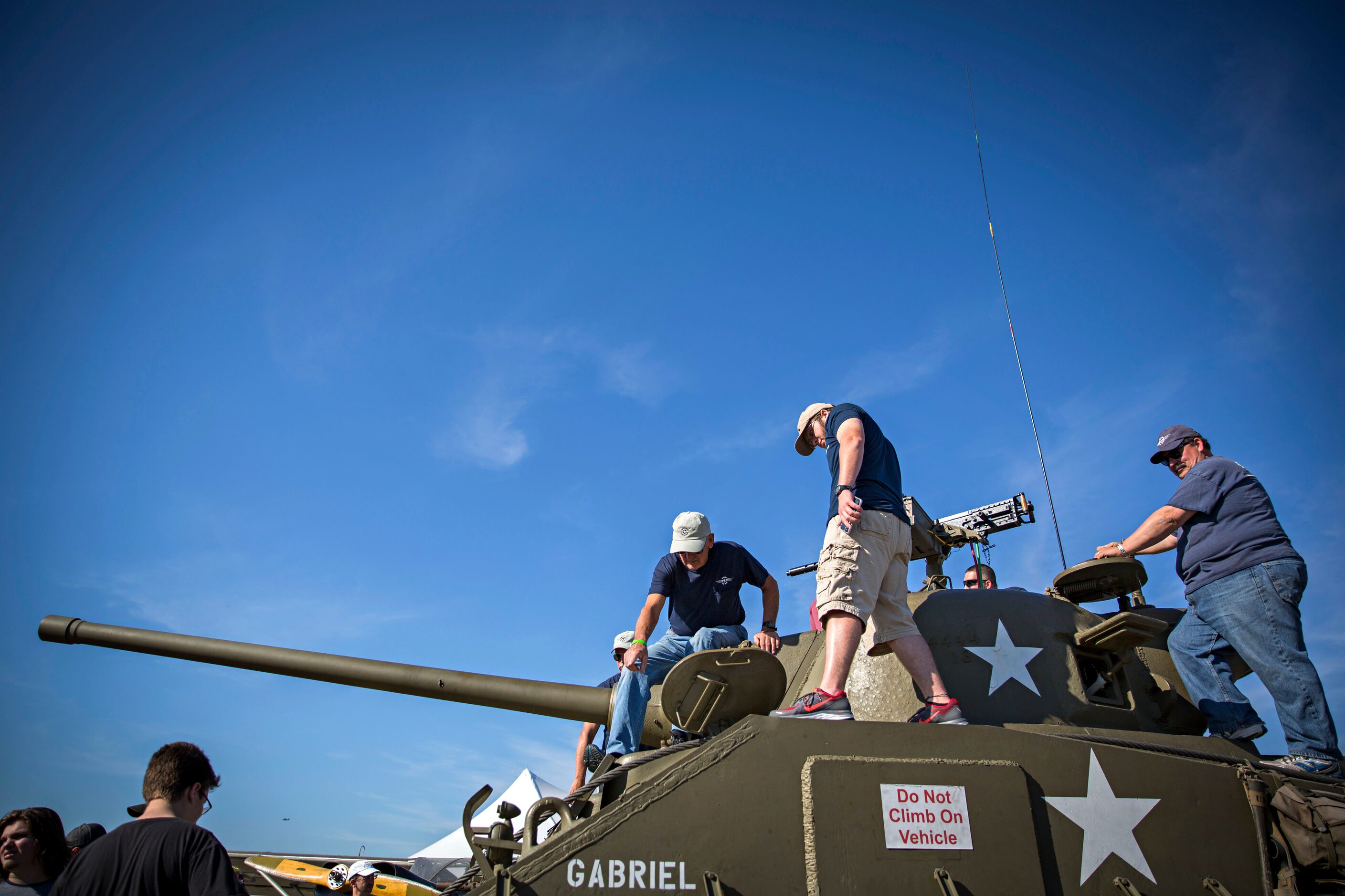 People climb on top of a tank during the Commemorative Air Force Wings Over Dallas WWII...