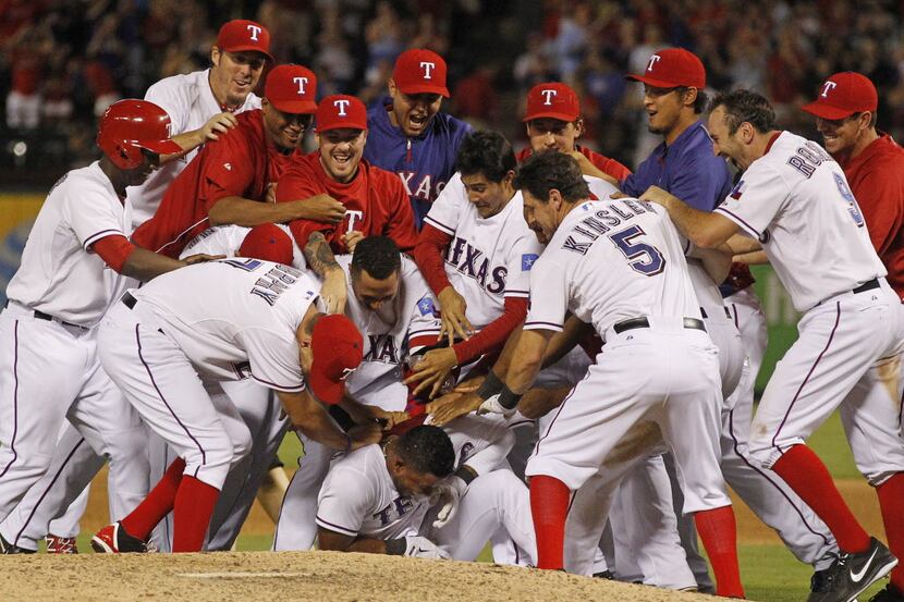 Texs Rangers' Elvis Andrus is mobbed by his teammates after his sacrifice fly scored Adam...