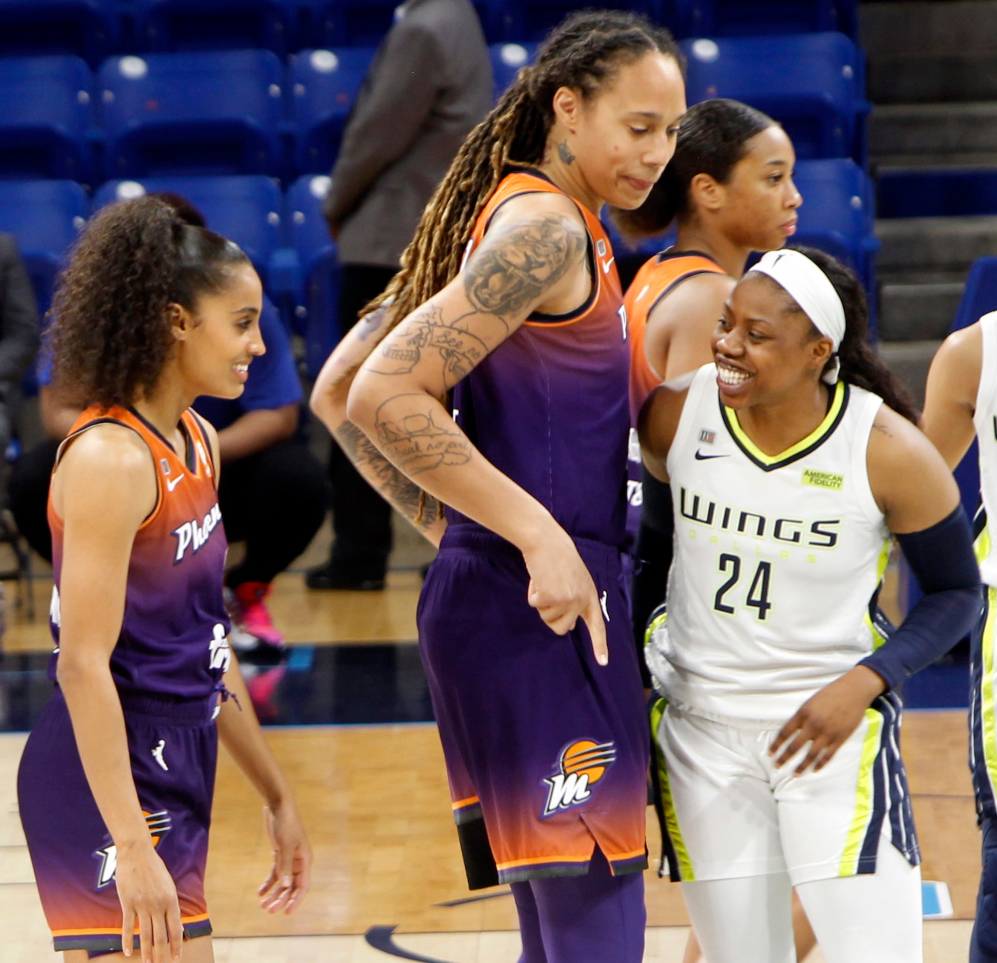 Dallas guard Arike Ogunbowale (24), right, peeks around 6'9" Phoenix forward Brittney Griner...