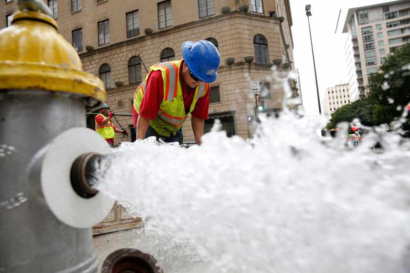 Luis Ortiz cleans off a muddy step ladder after fixing a water main break at St. Paul and...