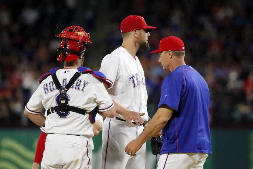 Texas Rangers catcher Bryan Holaday (8) watches as manager Jeff Banister, right, takes the...
