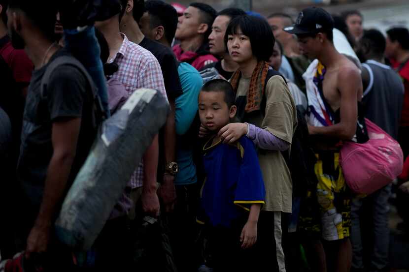 Migrantes chinos hacen fila para abordar una embarcación hacia Lajas Blancas después de...