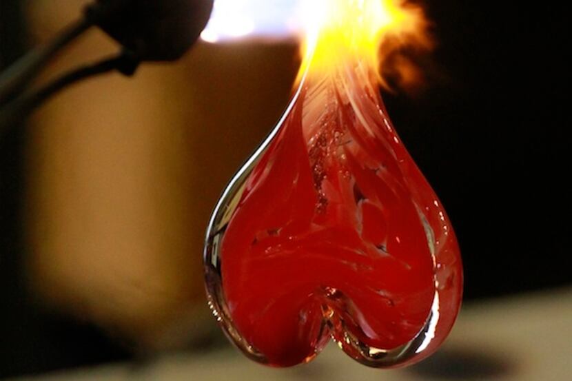 A glassblower finishes off a glass heart for a customer, in advance of Valentines Day, at...