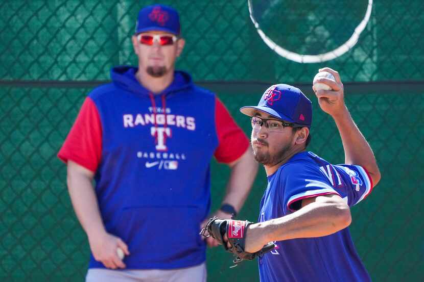 Texas Rangers co-pitching coach Doug Mathis watches pitcher Dane Dunning work in the bullpen...