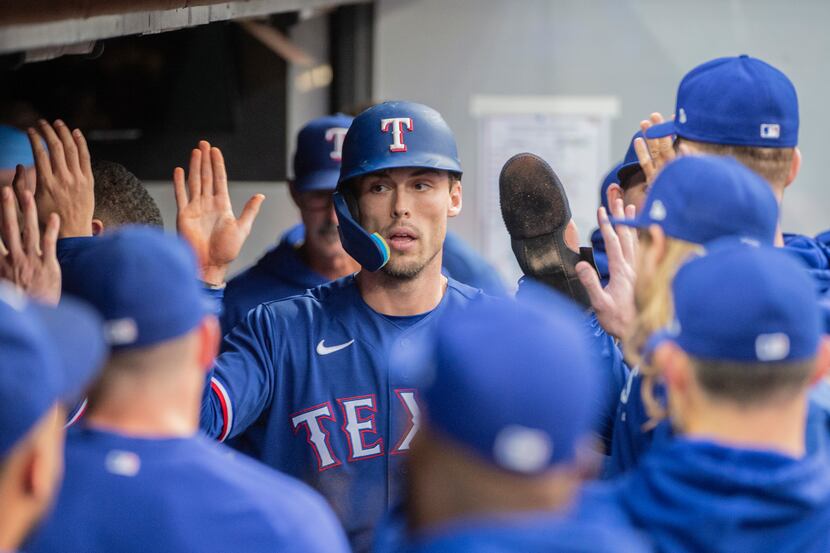 Texas Rangers' Evan Carter is congratulated after scoring on a double by Marcus Semien...
