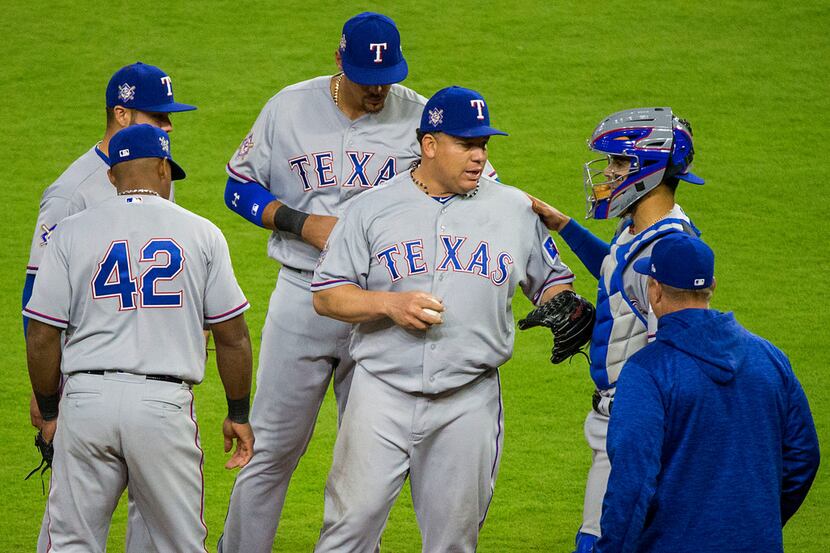 Texas Rangers starting pitcher Bartolo Colon is congratulated by teammates as he leaves the...