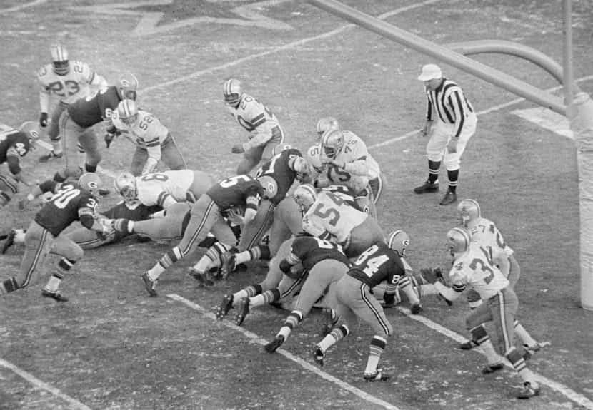 With seconds remaining, Green Bay Packers quarterback Bart Starr (15) bulls his way behind...