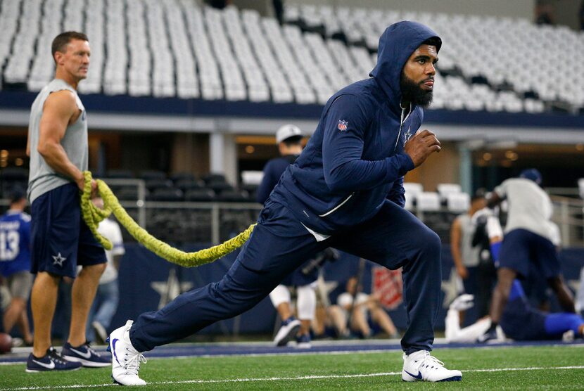 Dallas Cowboys running back Ezekiel Elliott stretches with the help of trainer Britt Brown...