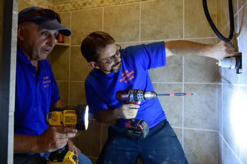 AM Plumbing co-owner Luis Lopez (left) and 10-year plumber Brian Robinson fix a low water...