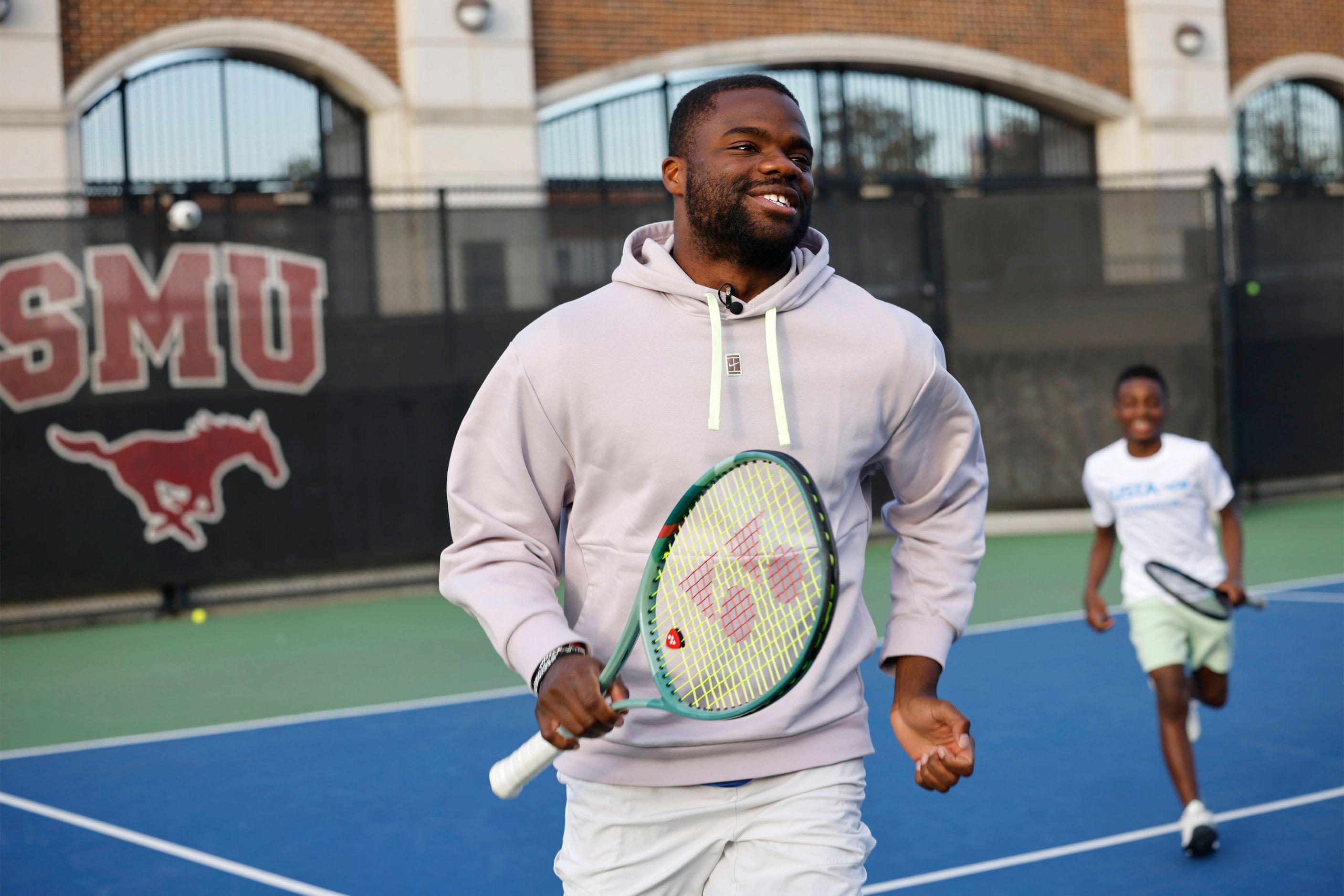 American tennis star Frances Tiafoe, left, runs with Jayden Kirkwood, 13, of Dallas Tennis...