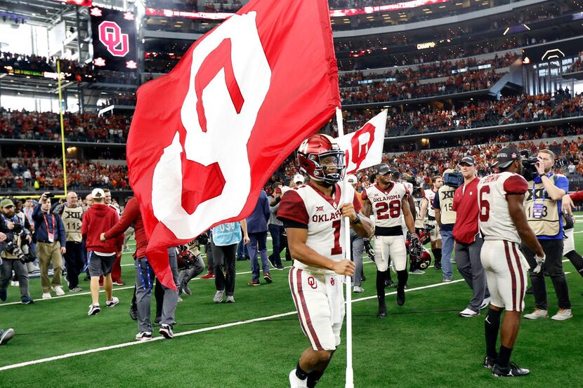 Oklahoma Sooners quarterback Kyler Murray runs around the field with the school flag after...