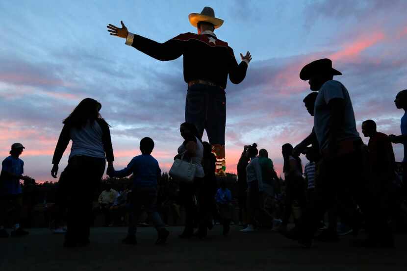 As the sun sets on the last day of the State Fair of Texas, fairgoers pass thru Big Tex...