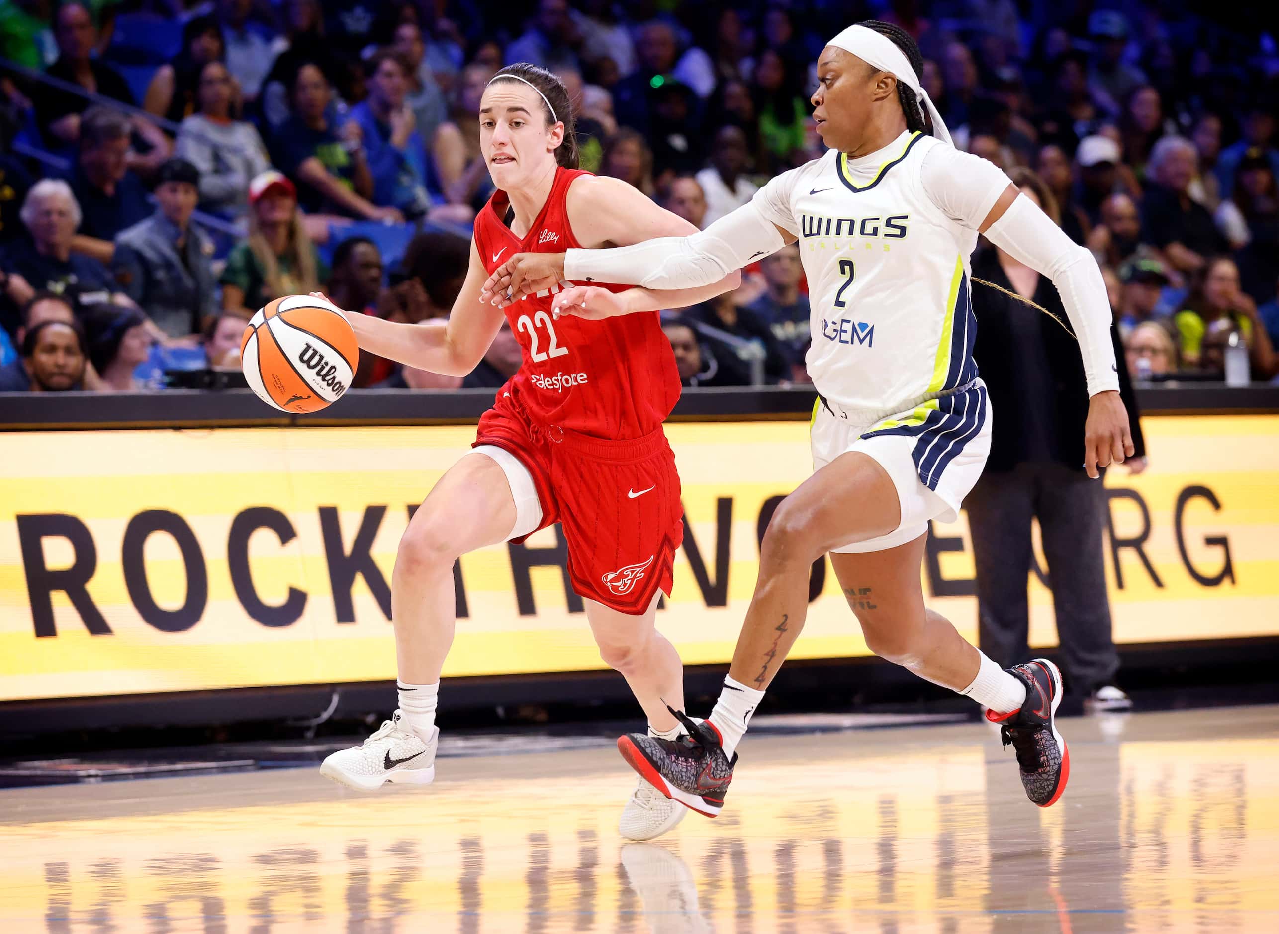 Dallas Wings guard Odyssey Sims (2) keeps pace with Indiana Fever guard Caitlin Clark (22)...