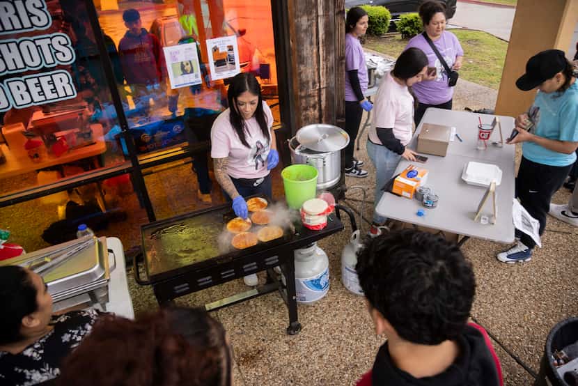 Erica Sanchez, center left, prepares birria tacos as family and friends raise money for her...