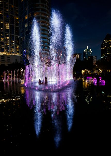 Children play in the Nancy Best Fountain while being unveiled with its first nightly water...