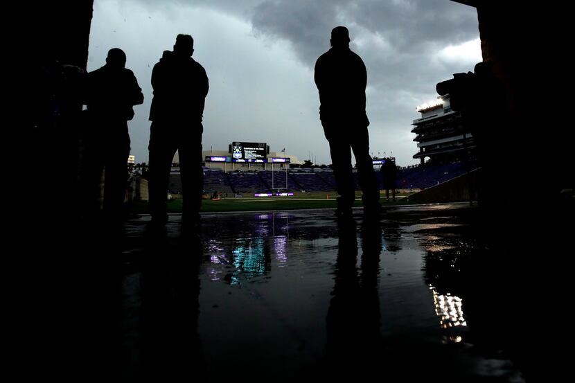 Game workers watch the clouds during a weather delay before an NCAA college football game...