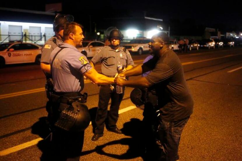 
A man walks up and greets police officers during nighttime demonstrations in Ferguson, Mo.
