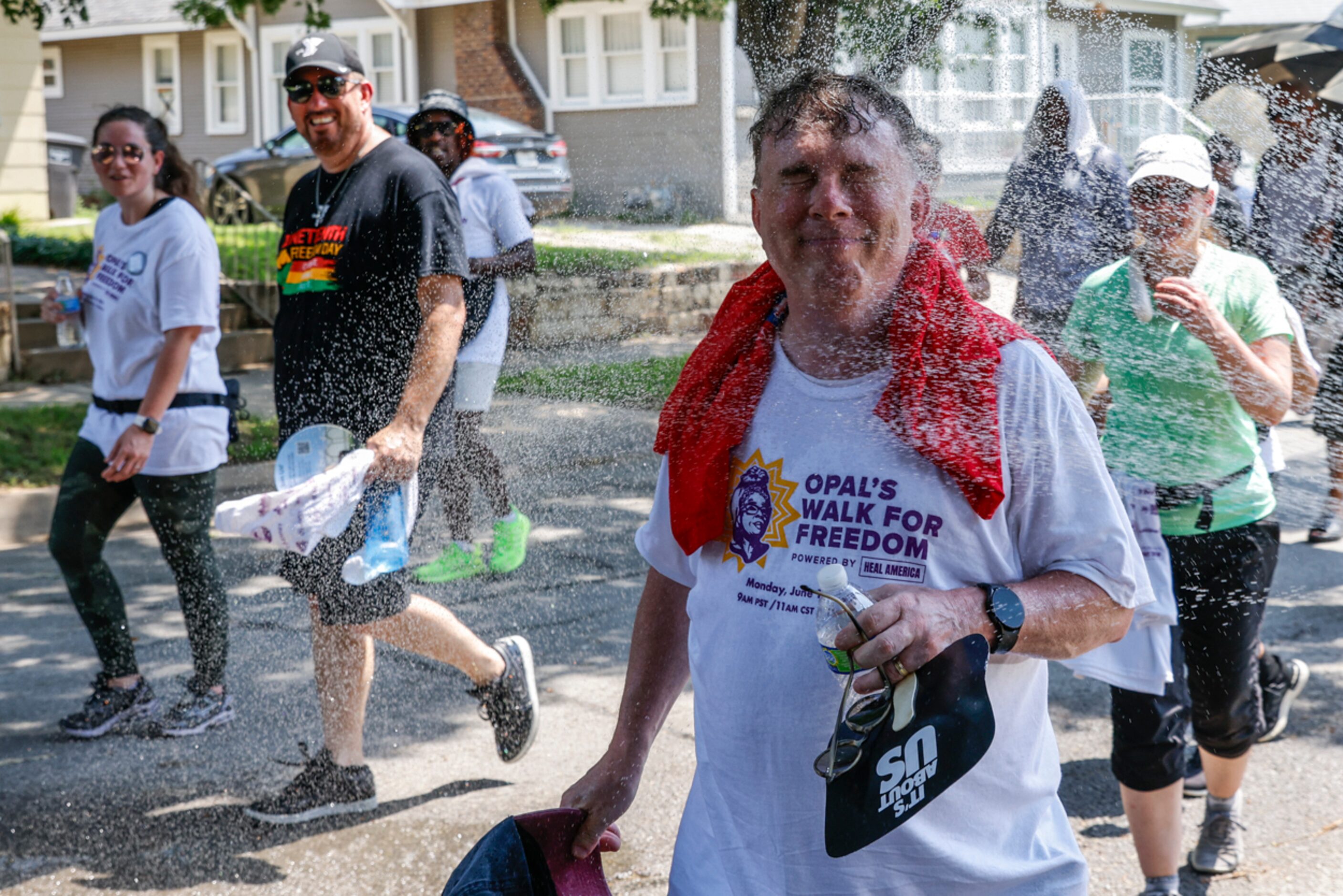 An attendee cools off as he walks by hose water during Opal's Walk for Freedom on Monday,...