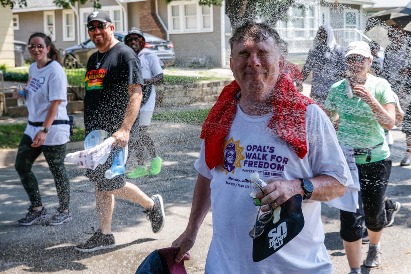 An attendee cools off as he walks by hose water during Opal's Walk for Freedom on Monday,...