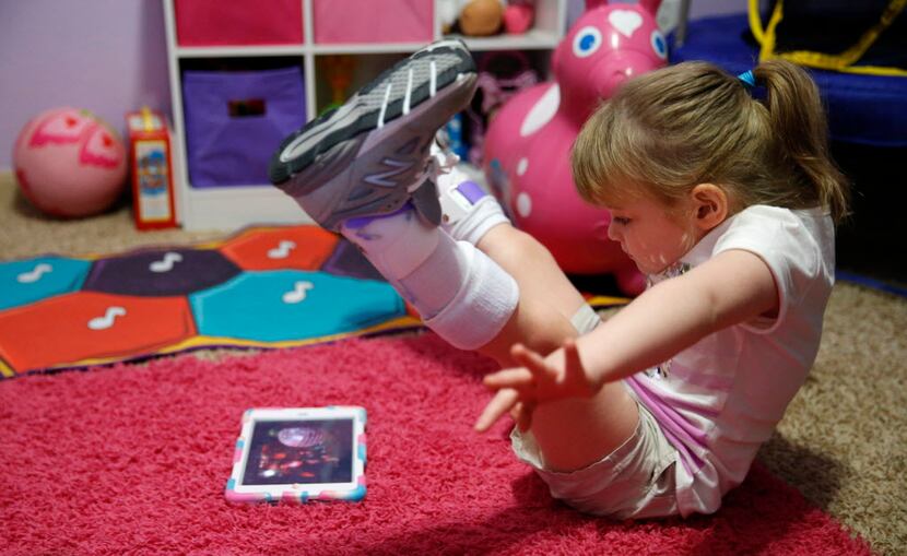 Karley Davis, 4, gets excited while watching a video on an iPad during a portion of her...