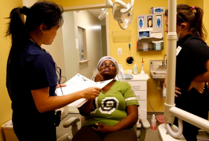 Dawn A. Wu, DDS , left, examines Carolyn Brock, center, with Ariel Sims, right, Nov. 18 at...