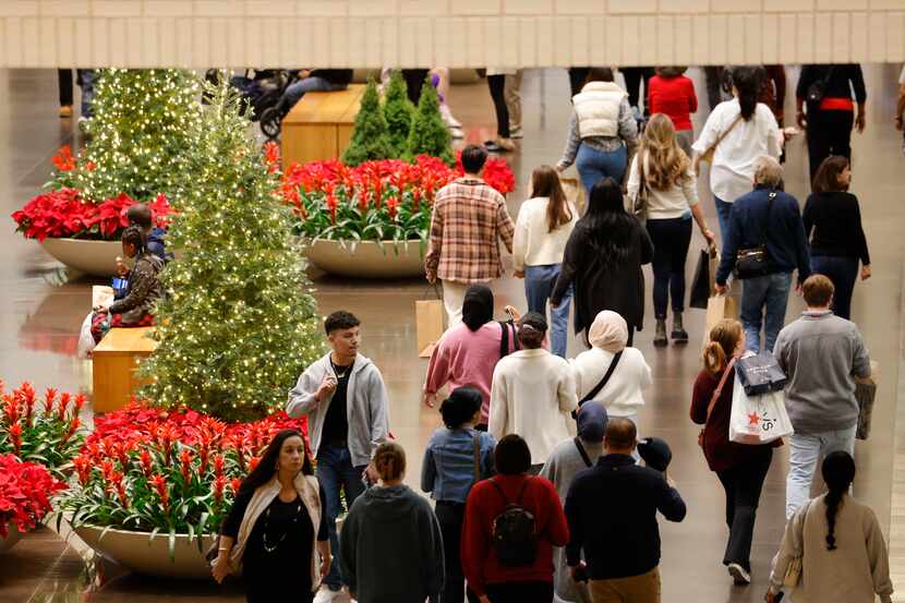 Shoppers walk through Dallas' NorthPark Center holding shopping bags on Thursday. With...