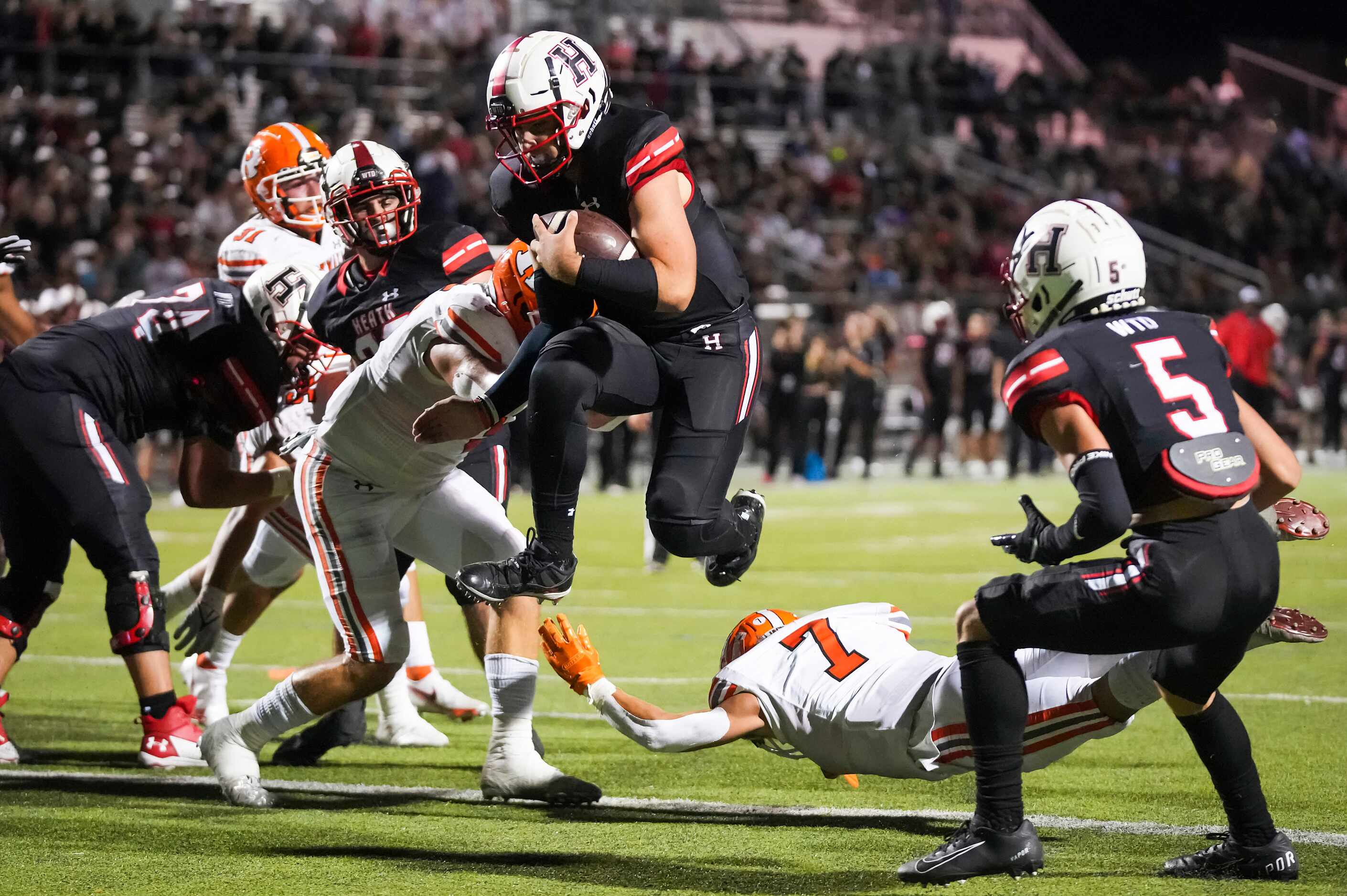 Rockwall-Heath quarterback Josh Hoover (17) leaps into the end zone past Rockwall defensive...