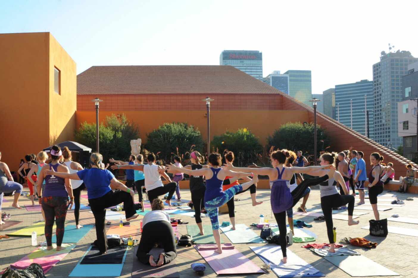 Yogis practice hand to big toe pose at the D-FW Free Day of Yoga Kickoff at the Latino...