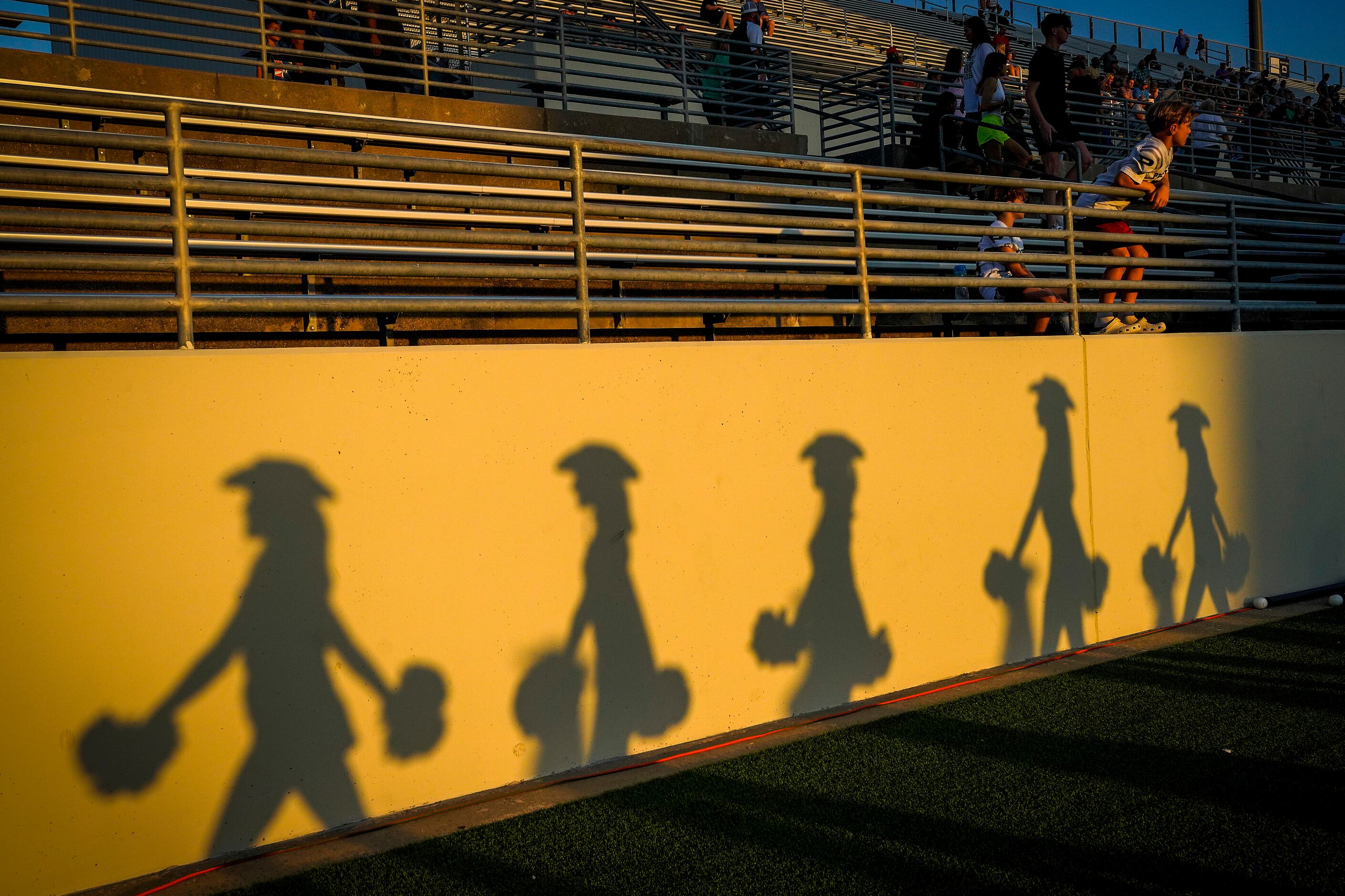 Members of the Prosper drill team cast shadows before a high school football game against...