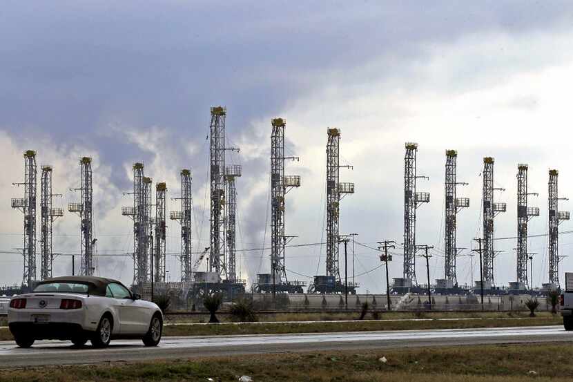 A car travels past drilling rigs on U.S. Highway 80, west of Farm-To-Market Road 1788,...