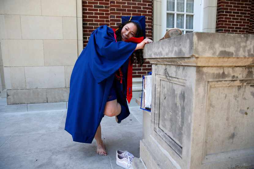 Wendy Birdsall switches shoes before graduation from SMU at McFarlin Auditorium on Friday.