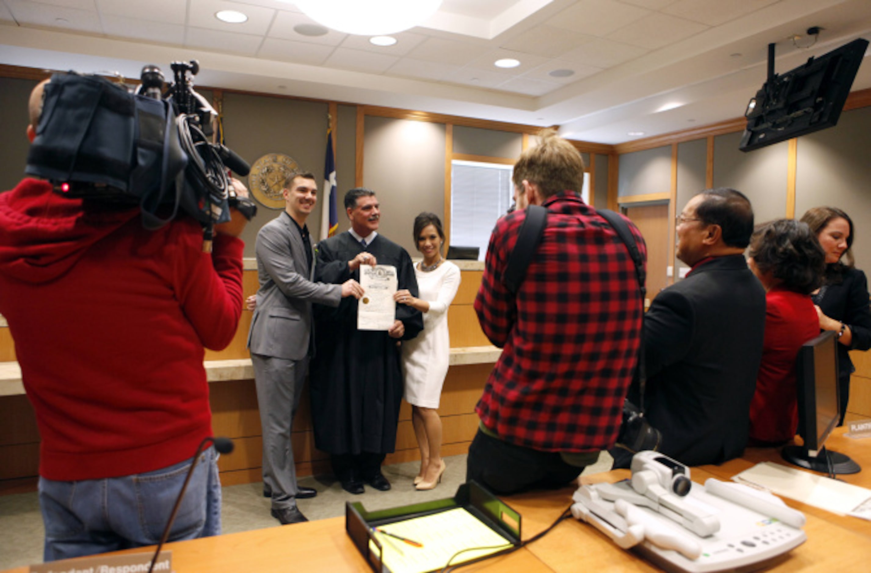 Troy and Alyssa Lannoo pose for pictures with Justice of the Peace Paul Raleeh after getting...