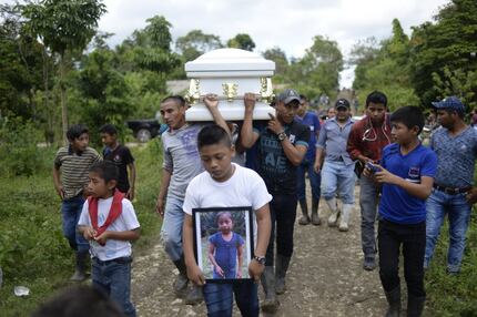 A boy carries a picture of Guatemalan seven-year-old Jakelin Caal, who died in a Texas...