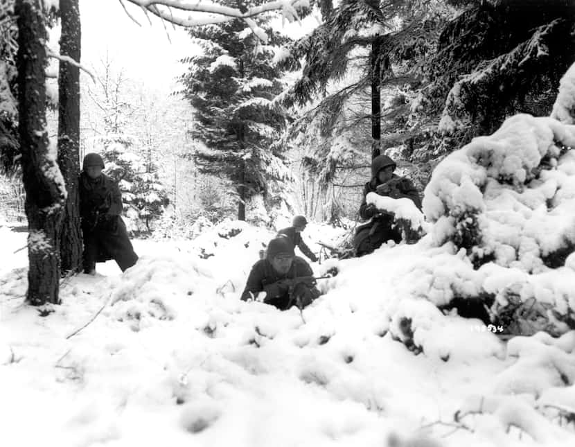 American infantrymen of the 290th Regiment move through fresh snowfall as they advance...