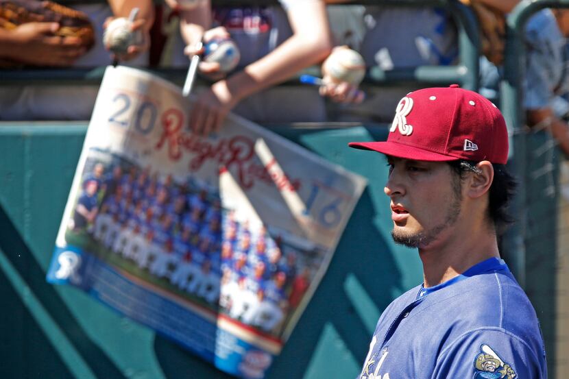 Texas Rangers pitcher Yu Darvish walks past autograph seekers into the dugout before the...