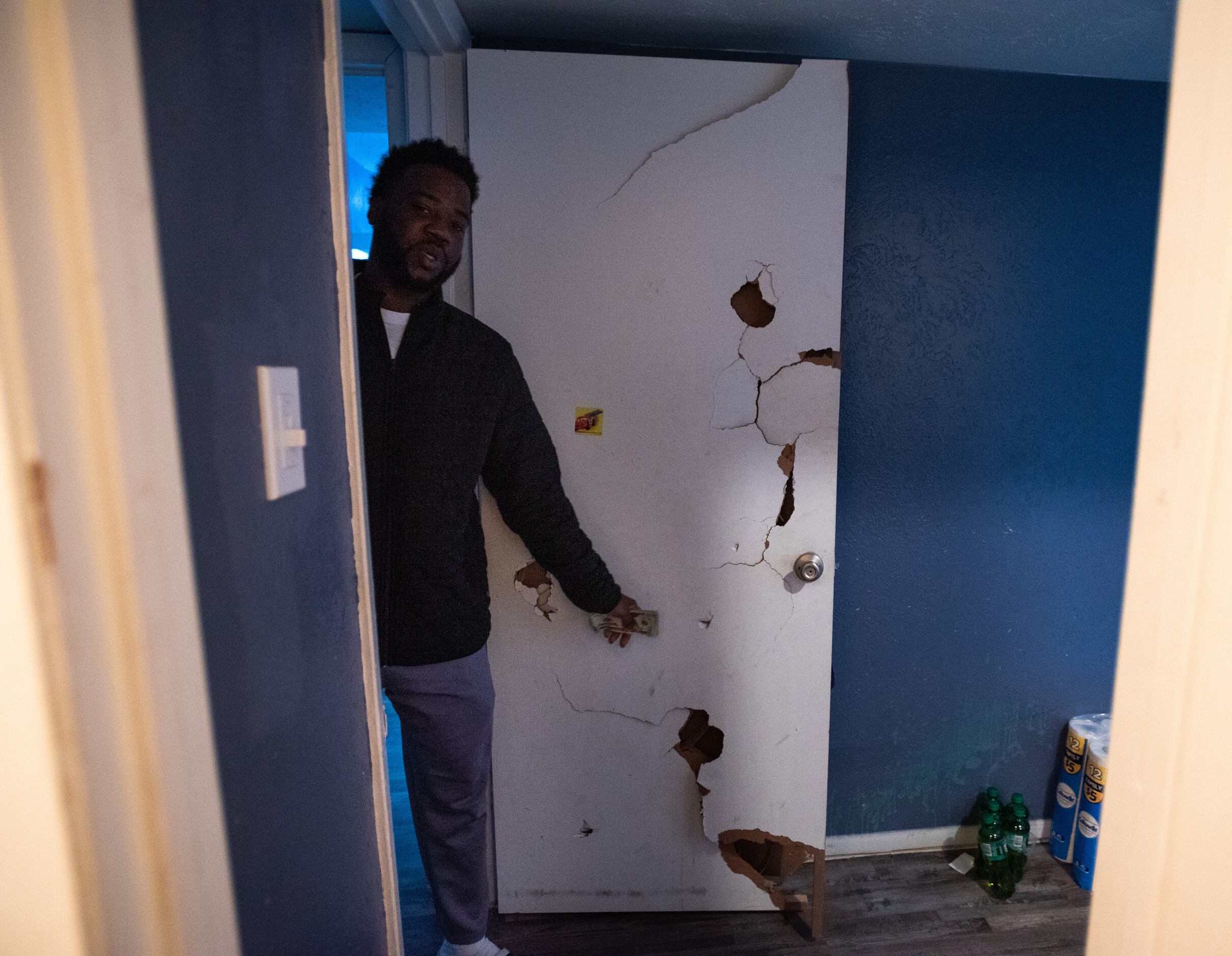 Deric Jones, 34, points at holes in his bedroom door that were never repaired before he...