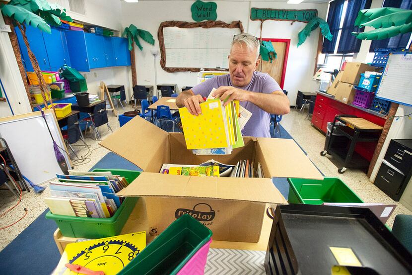 Teacher Bryan Matzke unpacks boxes of books inside his first-grade classroom at Thomas J....