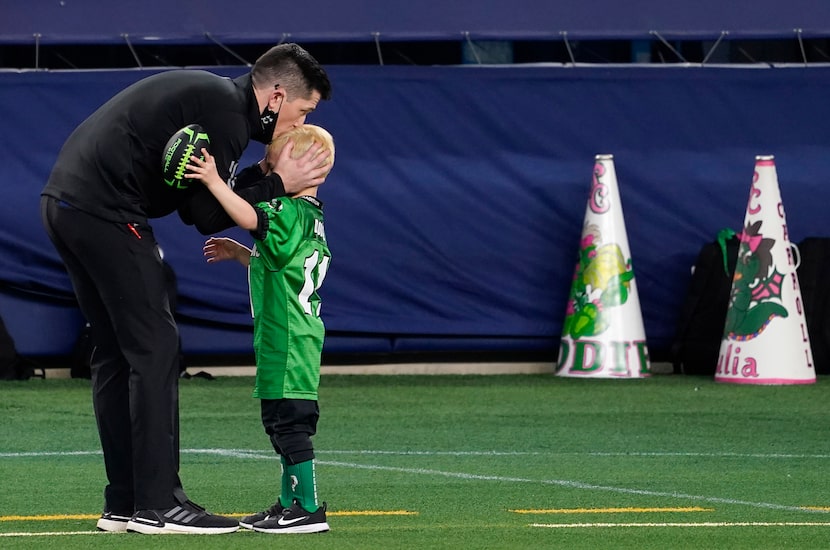 Southlake Carroll High School head coach Riley Dodge kissed his son Tate, 5, on the AT&T...