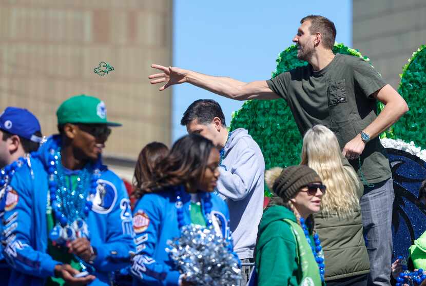 Dirk Nowitzki, the parade's grand marshal, tosses beads to people lined up along the route.