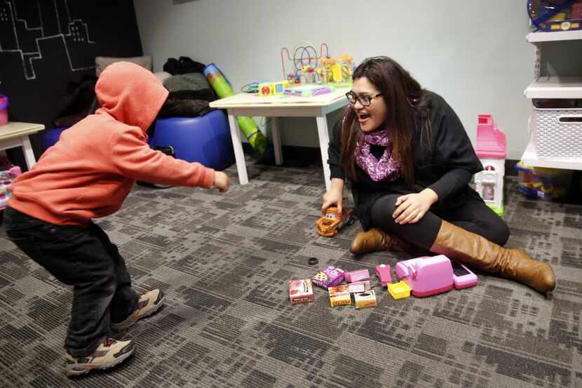 In this file photo, Laura De La Paz (right) plays with a child in the children's playroom at...