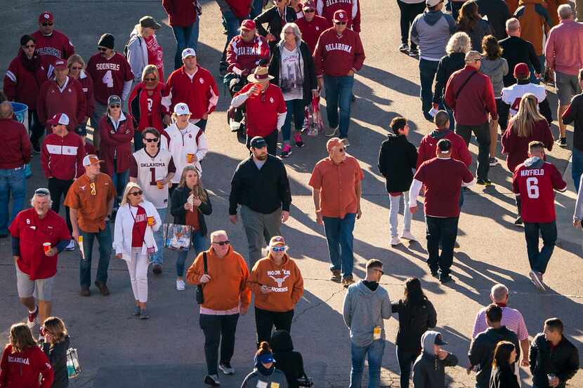Fans walk through the fair grounds on their way to the stadium before an NCAA football game...