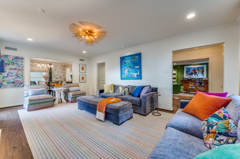 Living room with rainbow stripe rug, chevron upholstered slipper chairs, abstract art,...