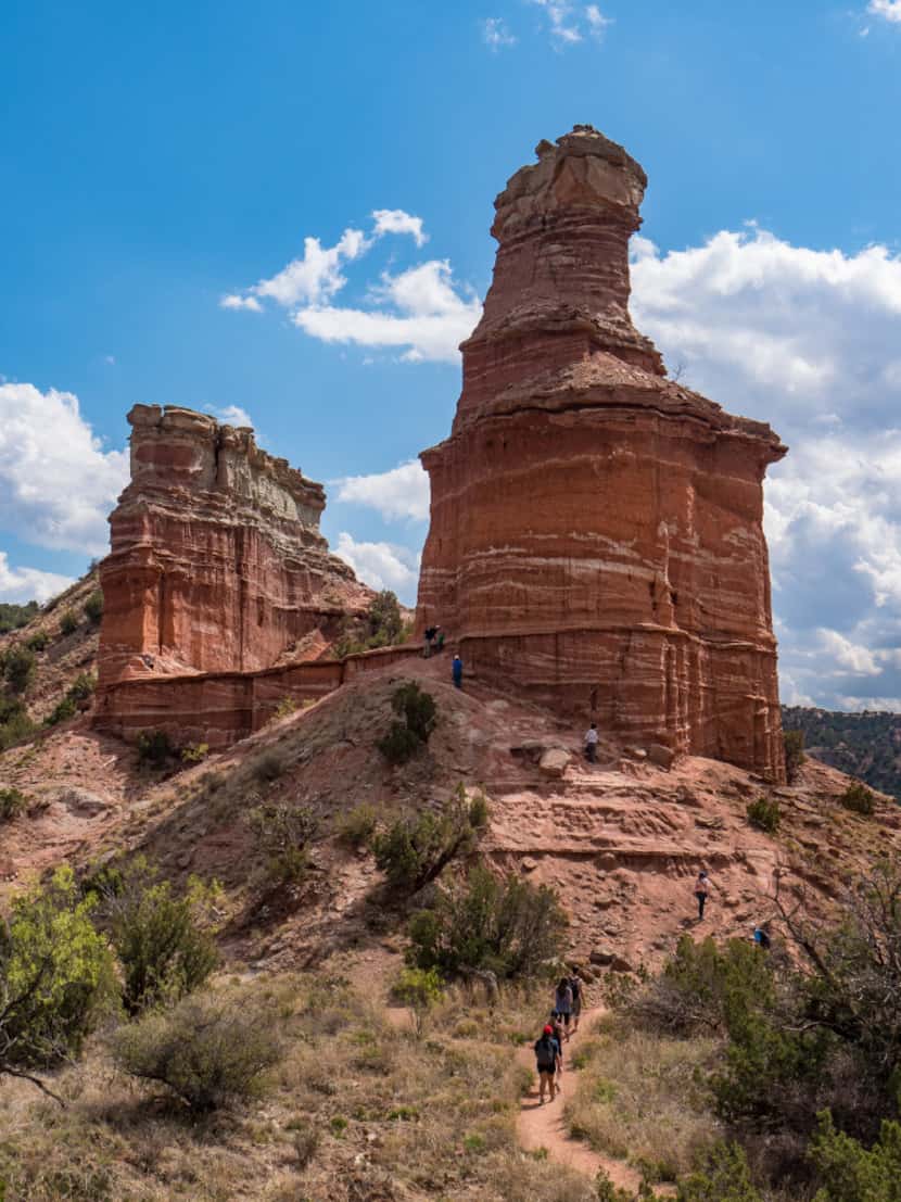 Hikers head toward the base of Lighthouse Rock, a 300-foot-high, two-tiered pillar that has...