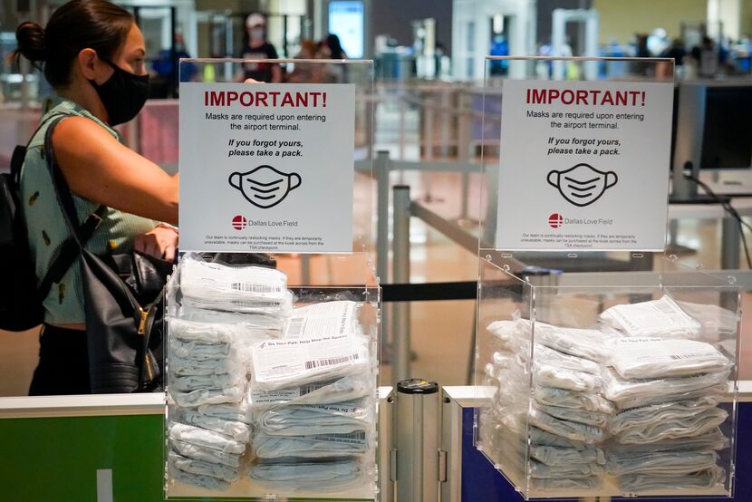 A passenger walked past complimentary face masks while entering the security checkpoint line...