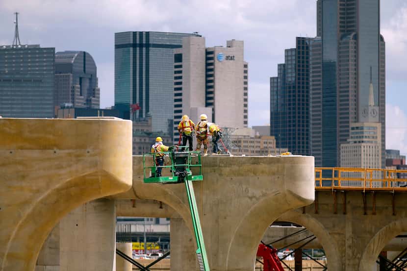 Construction crews work atop the bridge support columns and tops of the new northbound...