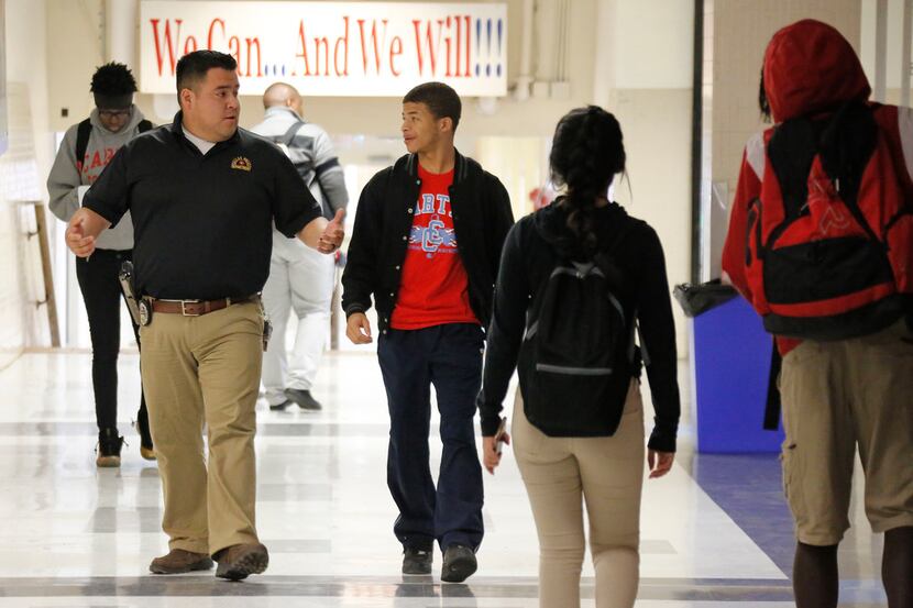 Dallas Police Officer Victor Guardiola (left) talks with Carter High School student Sedric...